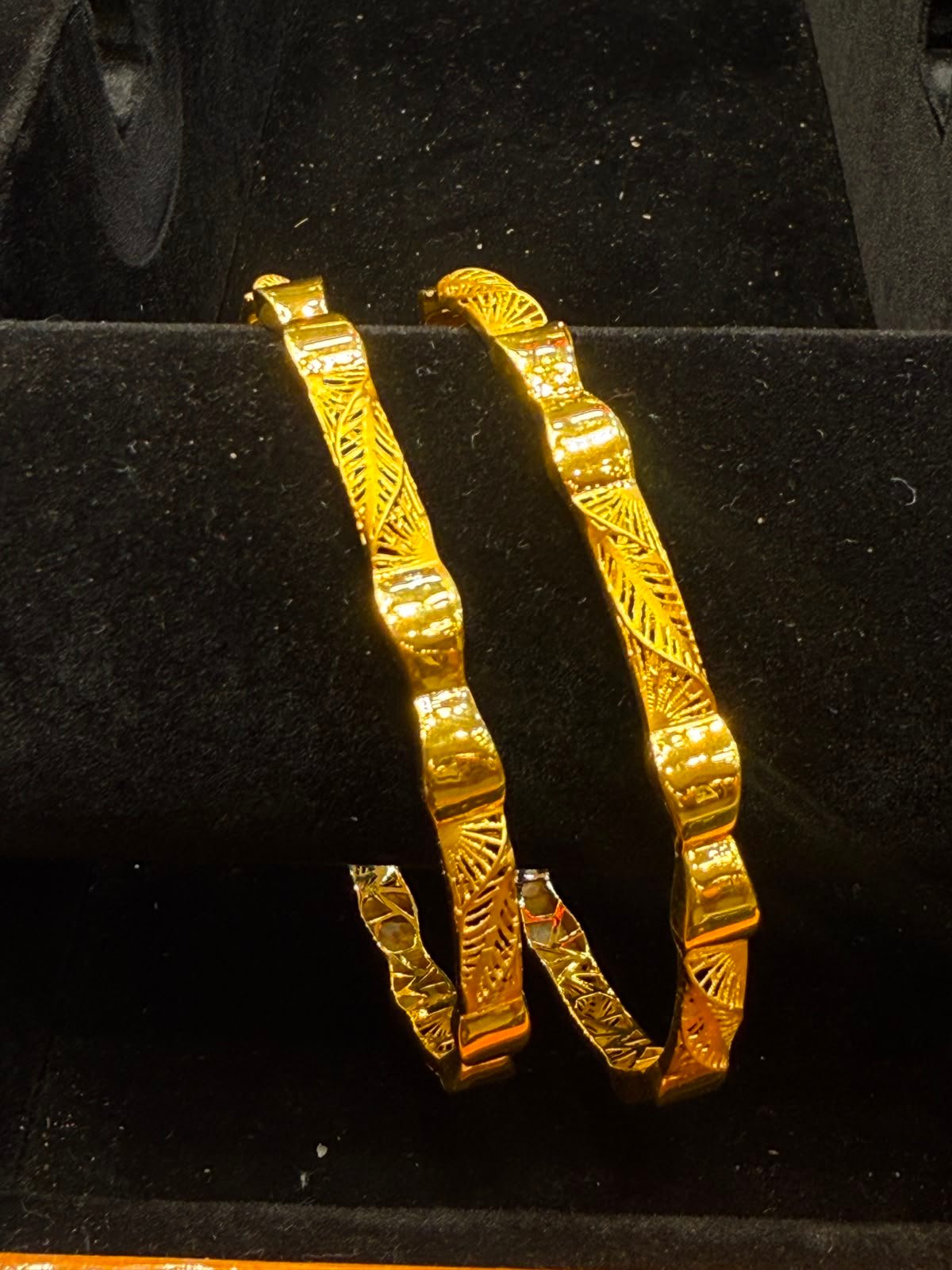 A pair of patterned gold bangles at Aina Gold