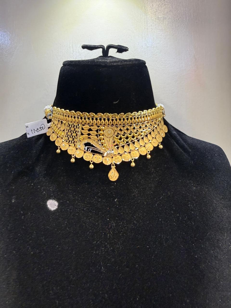 A gold choker with a basket-weave pattern and floral centre