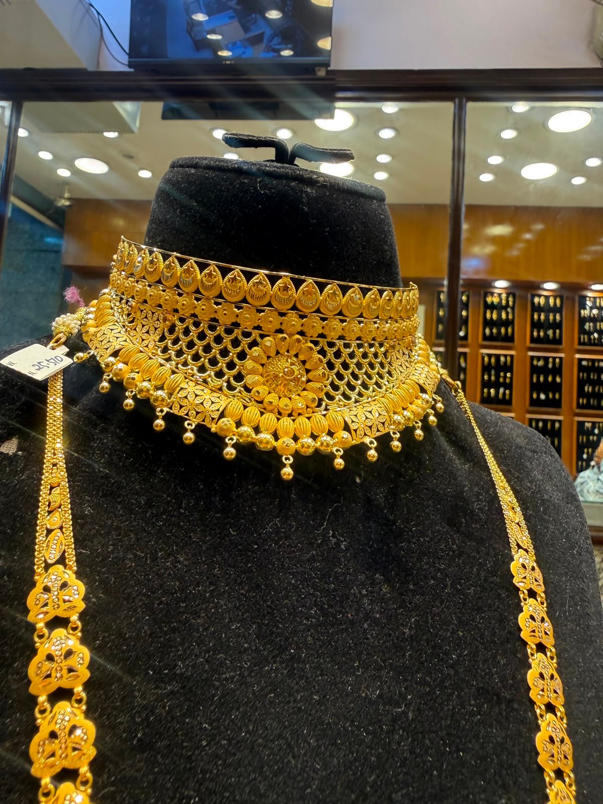 An elaborate gold bridal choker and necklace set on display at Aina Gold