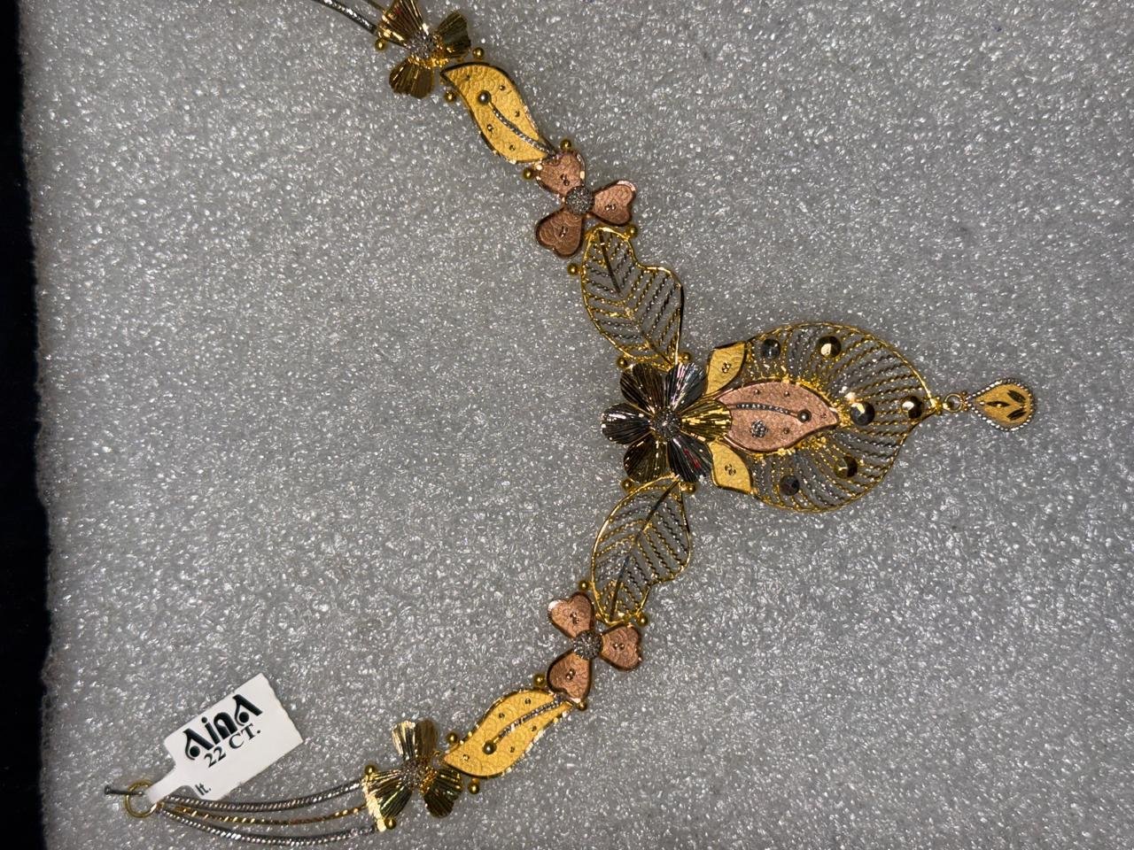 A gold necklace with hexagonal links and tassel drops