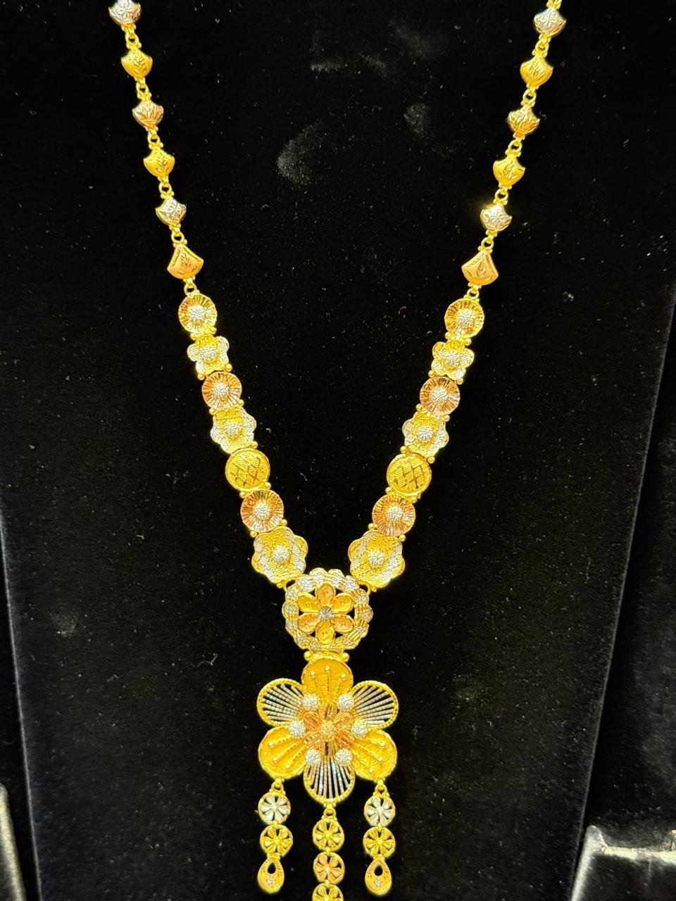 A tri-tone gold necklace with a floral pendant