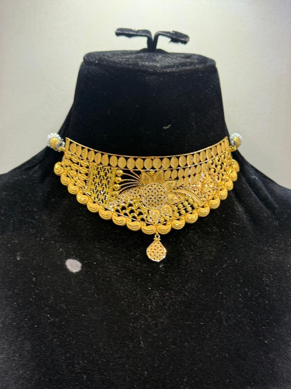 Detail of a tri-tone gold vine-pattern necklace, shown with its purity tag